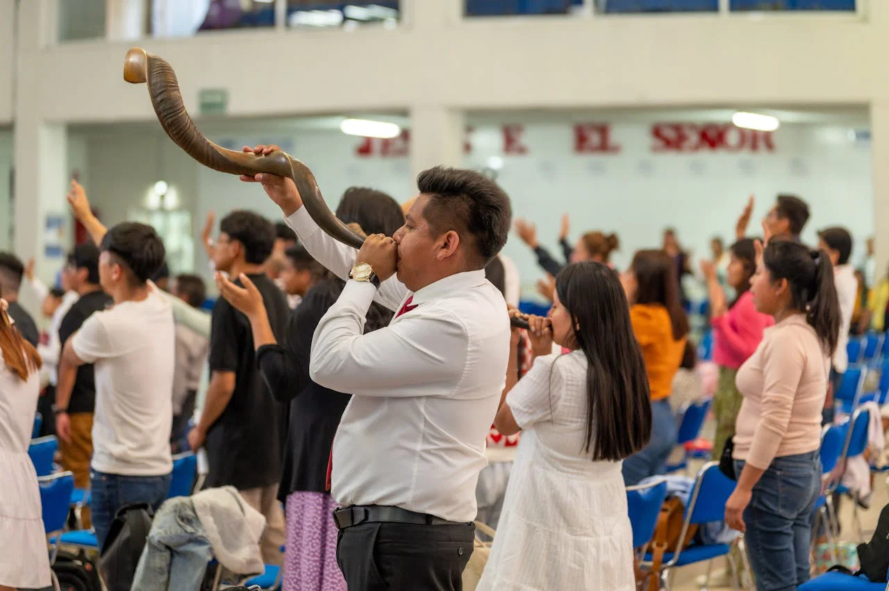 A group gathers for worship in Ciudad de México, with a man playing a shofar.