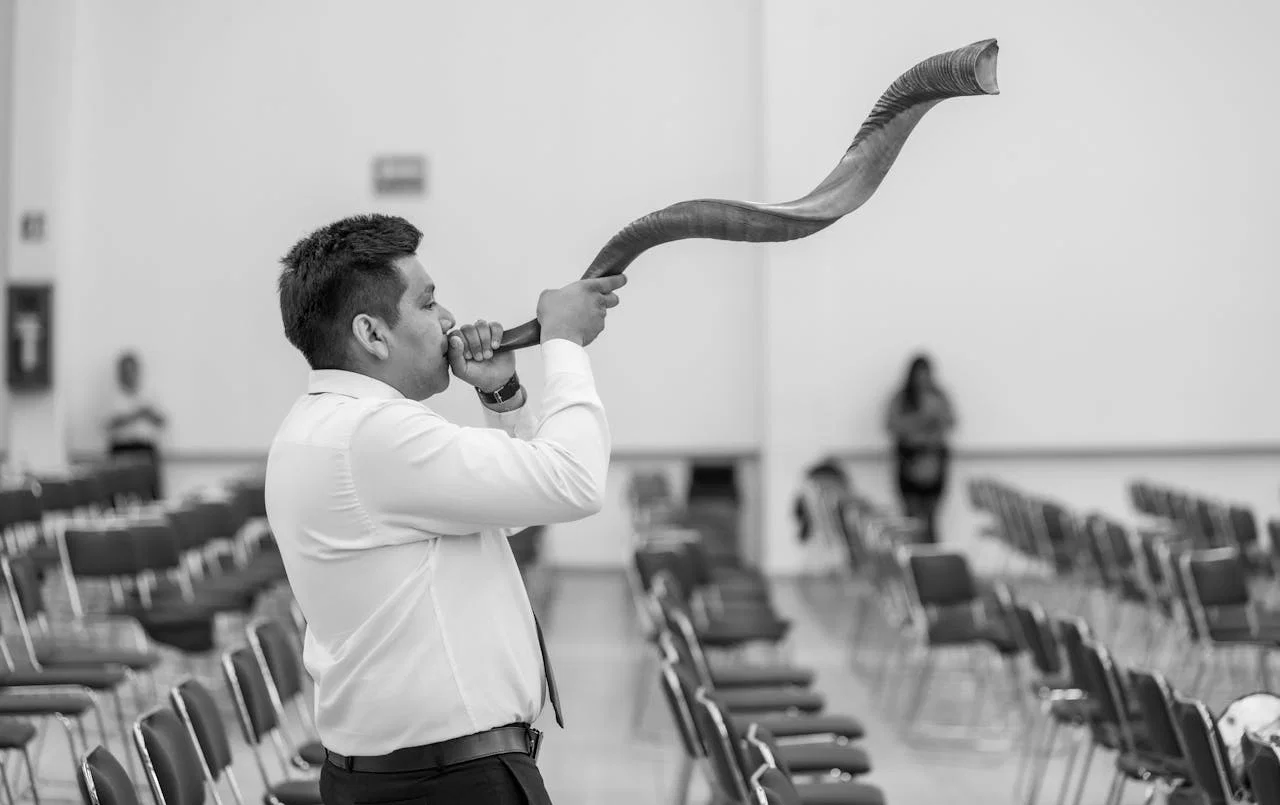 A man plays a shofar in a synagogue in Ciudad de México, capturing cultural tradition.