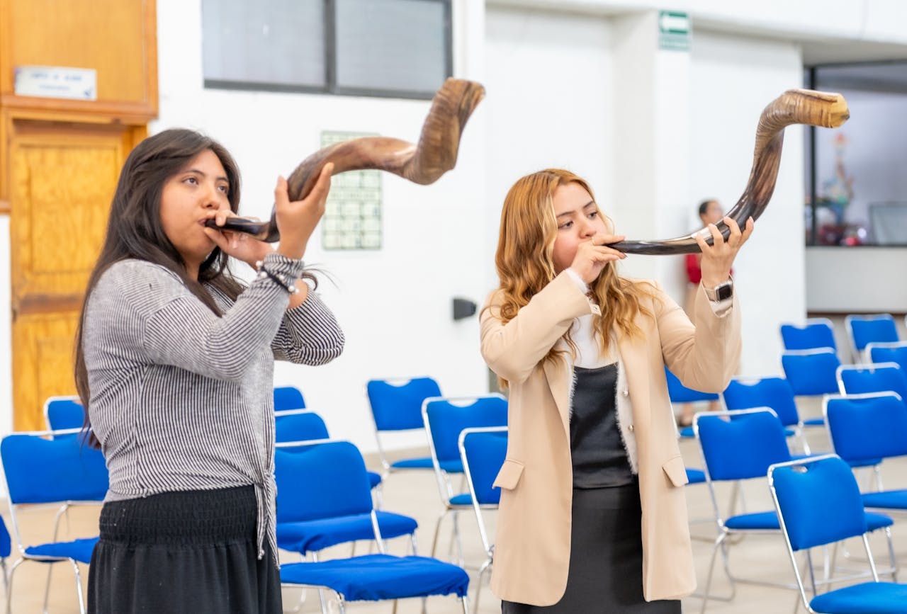 Two women playing shofars in a Ciudad de México gathering space.